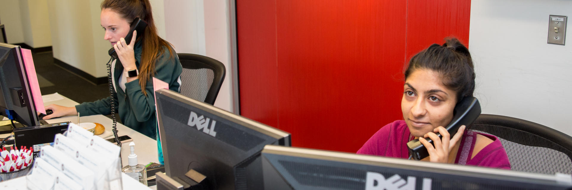 Two female students answer calls at the front desk of the Disability Services office